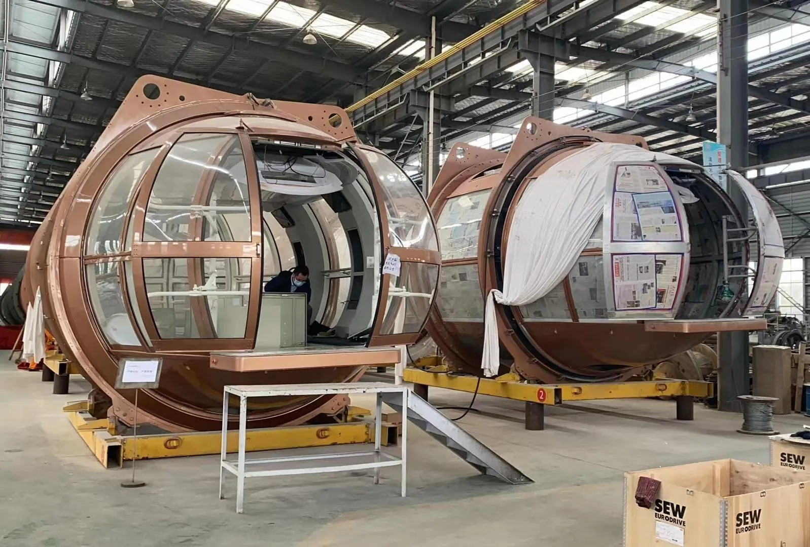 Enclosed observation-wheel capsules undergoing assembly inside Juma's factory
